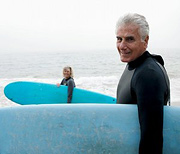Older couple holding their surfboards in front of ocean.