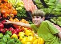 Boy reaching for a red pepper in super market.