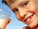 Boy smiles while holding glass of milk.