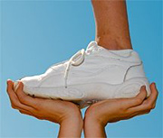 A person standing one-footed on the hands of another person.