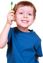 A smiling child brandishing a toothbrush.