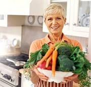 Woman holding large bowl of vegetables.