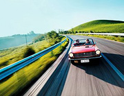 A man and woman cruising along a scenic road in their convertible.