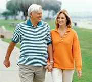 An elderly couple walking near beach.