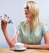 Woman overfilling a coffee cup with sugar.