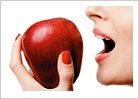 Woman taking a bite out of a red apple.