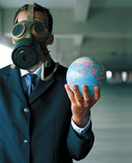 Man wearing gas mask holds the Earth in his hand.